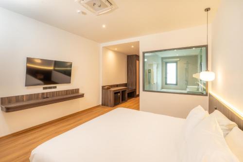 a hotel room with a bed and a tv at The Pinnacle Katanoi in Kata Beach