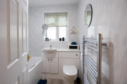 a bathroom with a toilet and a sink and a mirror at Three Bedroom House By Brookland Stays Serviced Accommodation Short Lets Cheltenham With Free WiFi in Cheltenham