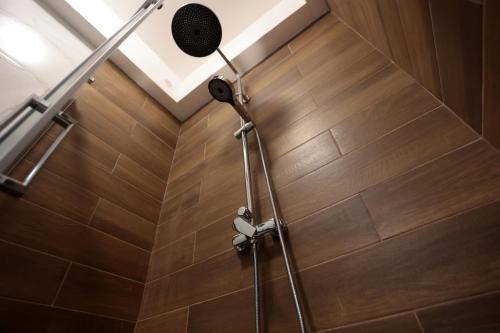 a shower head in a bathroom with a wooden floor at Casa Noal - a due passi da Ortigia e dal mare in Syracuse