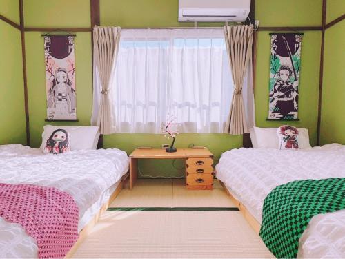 a bedroom with two beds and a window and a table at Sakura House in Yatomi 