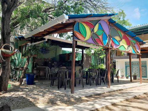 a patio with a colorful umbrella and tables and chairs at taganga macabi hostel in Santa Marta