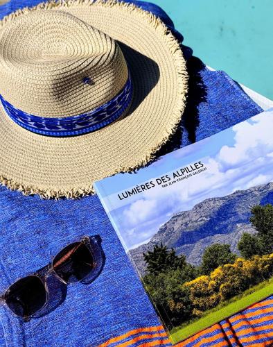 a hat and sunglasses sitting next to a book at Hôtel Mas Vidau Porte des Alpilles in Saint-Étienne-du-Grès