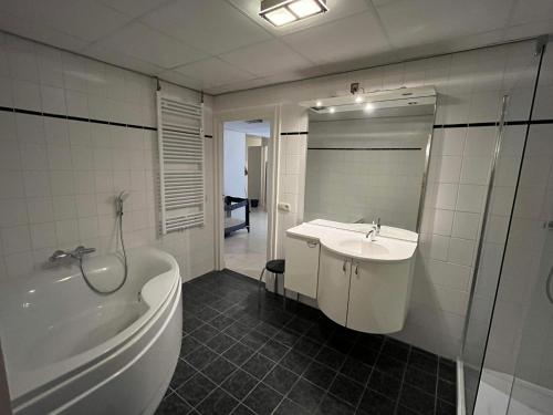 een badkamer met een bad en een wastafel en een ligbad bij Sea Dream in Oostende