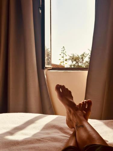 a persons feet on a bed with a window at Le Hameau des Cascades in Aghnajane