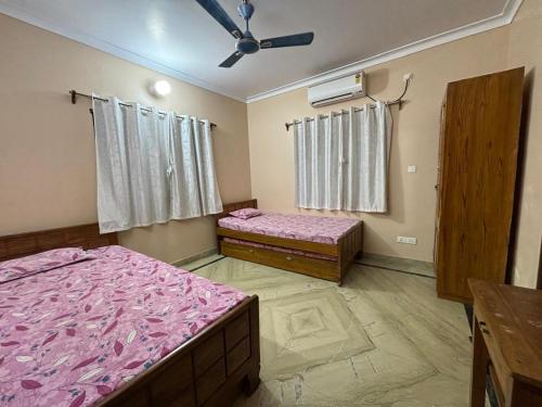 Un dormitorio con dos camas y un ventilador de techo. en Sudama Bhavan, en mayapur