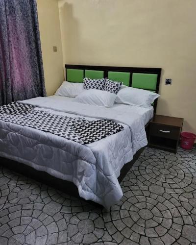 a bedroom with a large bed with a green headboard at Ohio city hotel in Owerri