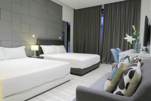 a hotel room with two beds and a chair at RR Cozy Studio & Suite in Singapore