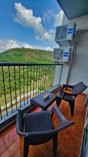 a balcony with two chairs and a table and a view at Luxury AC 2BHK Full Furnished with Sunrise View, Hill View, Pool, Kitchen, Ergonomic Workstation in Hinjewadi