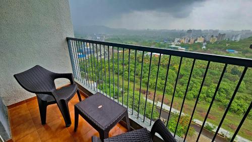 a balcony with two chairs and a table and a view at Luxury AC 2BHK Full Furnished with Sunrise View, Hill View, Pool, Kitchen, Ergonomic Workstation in Hinjewadi