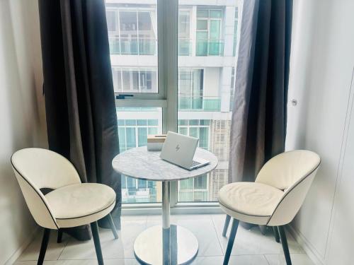 a table with two chairs and a laptop on it in front of a window at Hyde Sukhumvit 11 Bankok in Bangkok