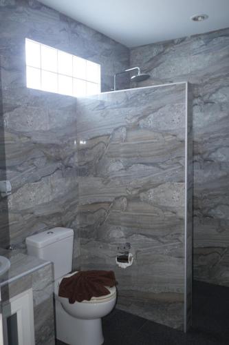 a bathroom with a toilet and a stone wall at Treff nad phop hotel in Patong Beach