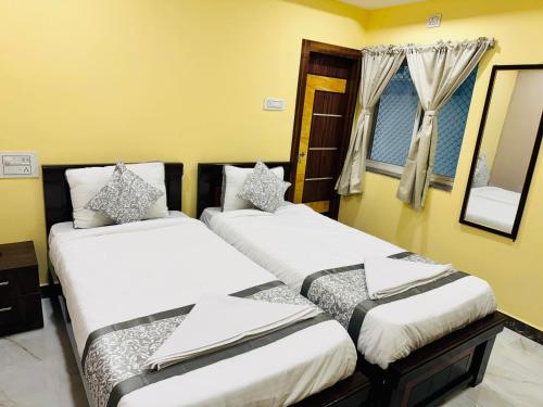 two beds in a room with yellow walls at HOTEL HYDERABAD PULSE in Shamshabad