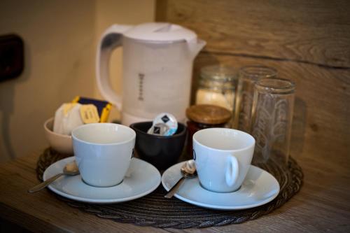 two cups and saucers on a table with a tea pot at Gästehaus Forellenhof in Pottenstein
