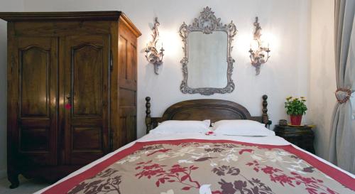 a bedroom with a bed with a wooden headboard and a mirror at Mas Des Collines in Fontvieille