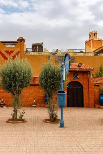 a blue clock in front of a building with two trees at Le Petit Riad Maison d'hôtes in Ouarzazate