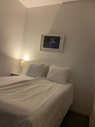 a white bed with white pillows and a picture on the wall at Köpingebro in Köpingebro