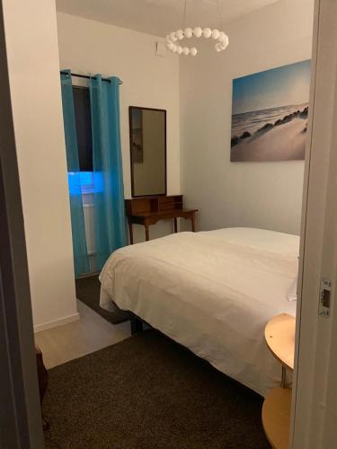 a bedroom with a white bed and blue curtains at Köpingebro in Köpingebro