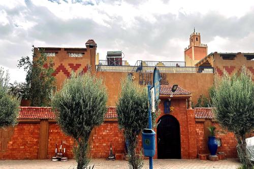 a red brick building with a gate and a tower at Le Petit Riad Maison d'hôtes in Ouarzazate