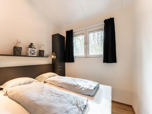 two beds in a bedroom with black curtains at Holiday Home in Hellendoorn near Forest in Hellendoorn