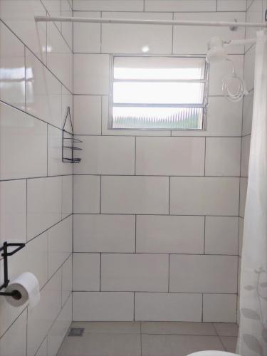 a bathroom with a white tiled shower with a window at Casa Monjardim in Vitória