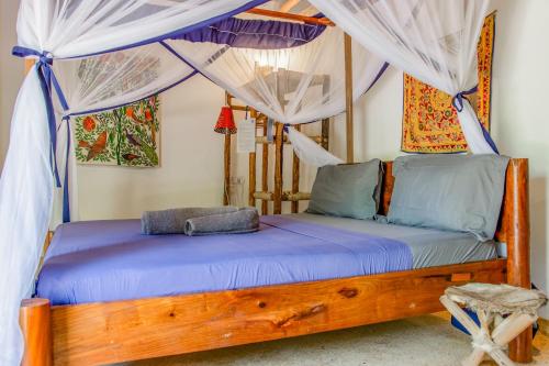 a bedroom with a wooden bed with mosquito nets at Kameleon Blue in Kizimkazi