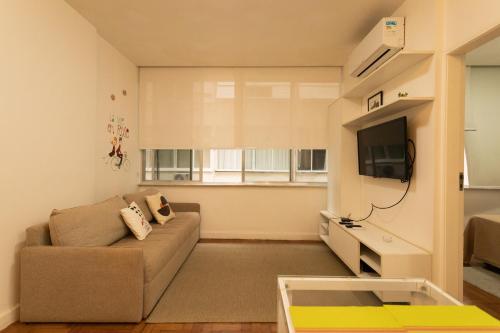 uma sala de estar com um sofá e uma TV em SUH Copacabana 110 Beach Plus no Rio de Janeiro