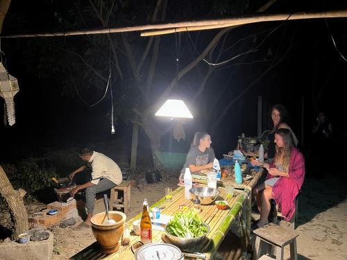 a group of people sitting around a table at the beach at Himmapun Farmstay in Ban Pa Ngiu