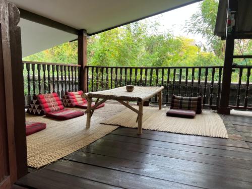 a wooden deck with a table and some pillows at Himmapun Farmstay in Ban Pa Ngiu