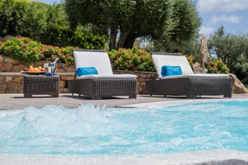 two wicker chairs sitting next to a swimming pool at Villa Smeralda Punta Lada Porto Rotondo in Porto Rotondo