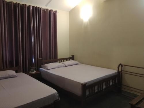 a room with two beds and a light on the wall at Kandy Vayo Villa in Digana