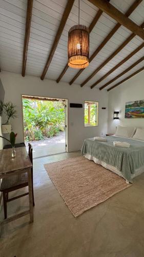 a bedroom with a bed and a table and a chandelier at Viva Vida Caraiva in Caraíva