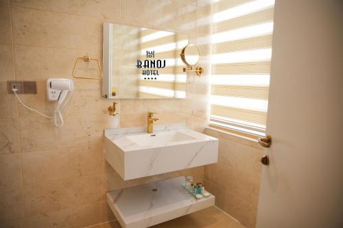 ein Badezimmer mit einem weißen Waschbecken und einem Spiegel in der Unterkunft Banoj Hotel in Erbil