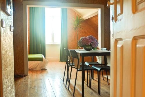 a dining room table with chairs and a vase of flowers at Aveiro Train Studios in Aveiro