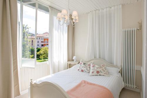 Un dormitorio con una cama blanca con almohadas y una ventana. en Villa Rachel Trilo, en Intra