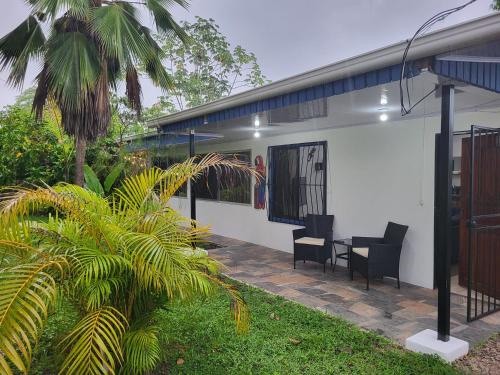 a white house with two chairs and a table at Villa Milagro in Parrita