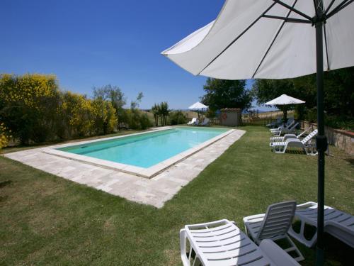 a swimming pool with lounge chairs and an umbrella at Farmhouse in Tuscany near Siena & Hot Springs in Castelnuovo Berardenga