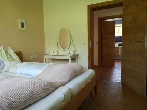 a bedroom with a bed and a table with a mirror at Apartment Stoderzinken, gemütlich und ruhig in Gröbming