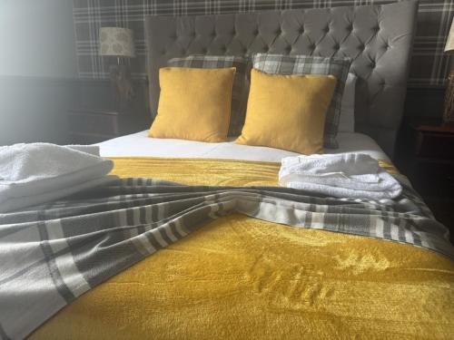 a bed with yellow and gray sheets and yellow pillows at Ivy By The Sea in Scarborough