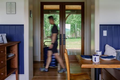 a man is walking through the door of a house at The Indigo House, an adults only, modern bed and breakfast for outdoorsy humans and kind dogs in Afton