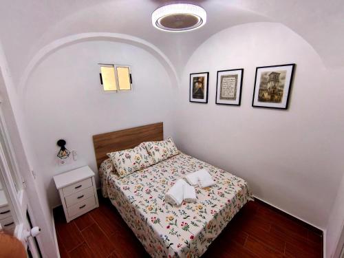 a small bedroom with a bed and pictures on the wall at Casita ENTREARCOS in Arcos de la Frontera