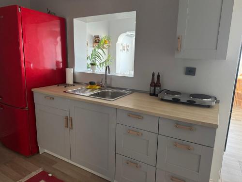 una cucina con un lavello e un frigorifero rosso di Tarihi Asansör Sokağında Daire a Smirne