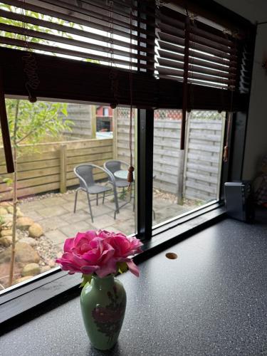 a vase with pink flowers sitting on a table in front of a window at The Pigeon Hole in Ribe