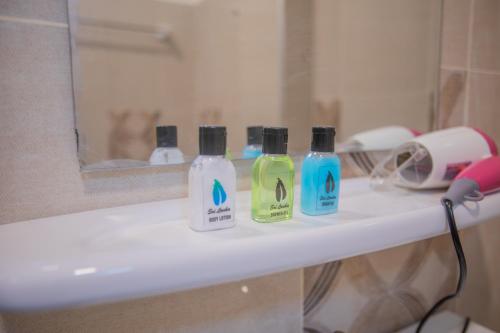 three bottles of detergent sitting on a bathroom sink at The Cozy Nest - Sigiriya in Sigiriya