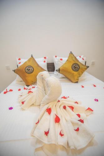 a bed with white sheets and red flowers on it at The Cozy Nest - Sigiriya in Sigiriya