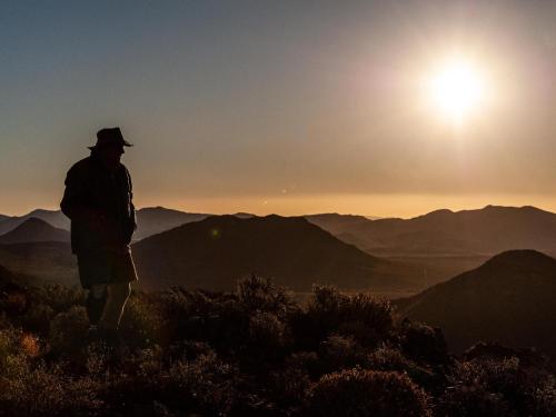 a man standing on top of a mountain looking at the sunset at Rooilande Guest Farm in Laingsburg