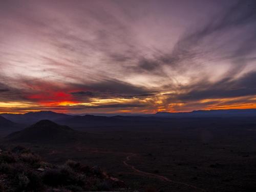 a sunset in the mountains with a cloudy sky at Rooilande Guest Farm in Laingsburg