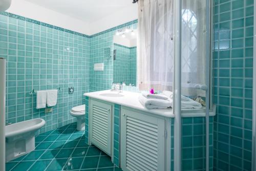 a blue tiled bathroom with a sink and a toilet at Villa Smeralda Punta Lada Porto Rotondo in Porto Rotondo