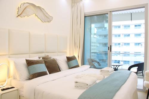 a white bed in a room with a large window at Dubai Marina 1BR with Balcony, Near Metro, Walk to JBR beach & Marina Promenade in Dubai