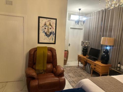 a living room with a chair and a desk with a computer at Maison Norelle at Isivuno House in Gillitts