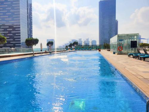 a large swimming pool on the roof of a building at Pearl Club Al Reem Island 2 Bedrooms With Pool , Gym and Tennis Court in Abu Dhabi